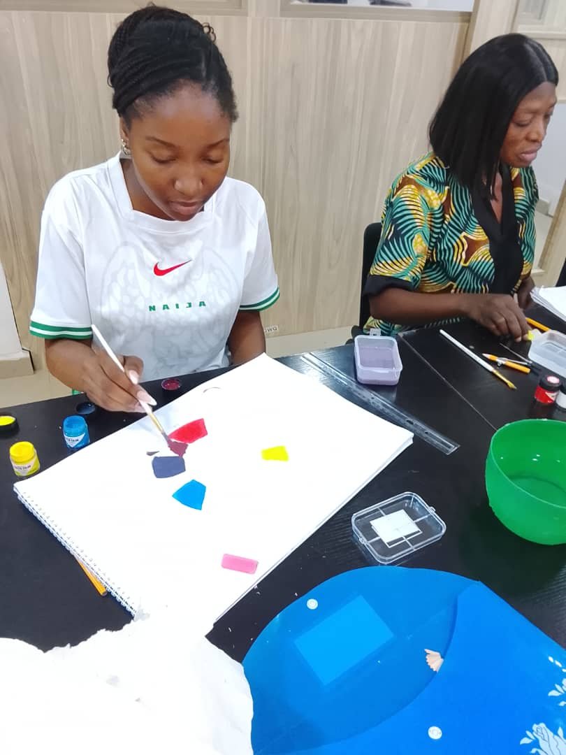 Two students mixing and laying down colour swatches on a pad during a studio session